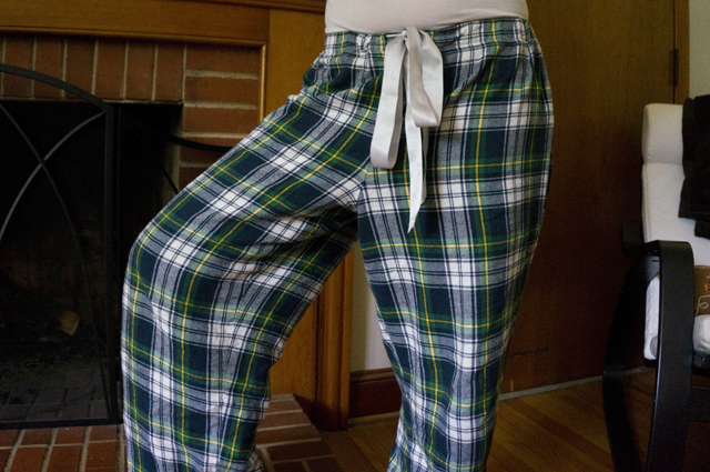 Legs akimbo, showing the fullness of the tartan pajama pants through the front of the hip and thigh