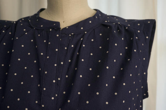 A close-up of a woman's sleeveless summer top, showing the gathers at the front neckline and shoulder