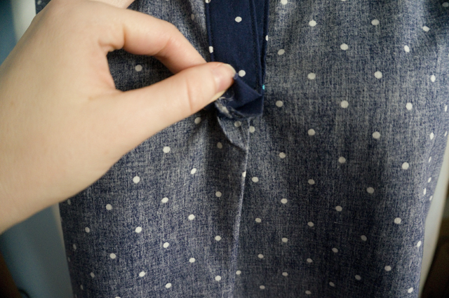 A close-up of a woman's sleeveless summer top turned inside-out, showing how the placket intersects with the front pleat