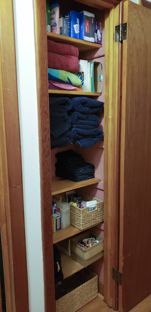 The inside of the same linen closet after being organized, with empty space on two of the six shelves