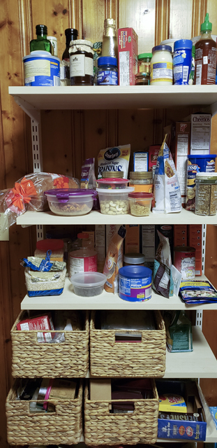 A freestanding pantry shelf unit with a hodgepodge of boxes, jars, and food storage containers