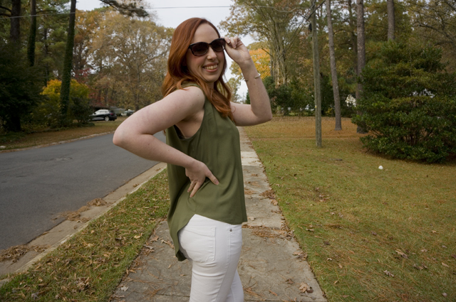 Caitlyn is turned to the side to show the deep armhole, voluminous fit, and high-low hem of her sleeveless summer blouse