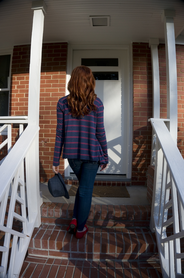 Caitlyn is facing away from the camera to show off the back of her open-front cardigan