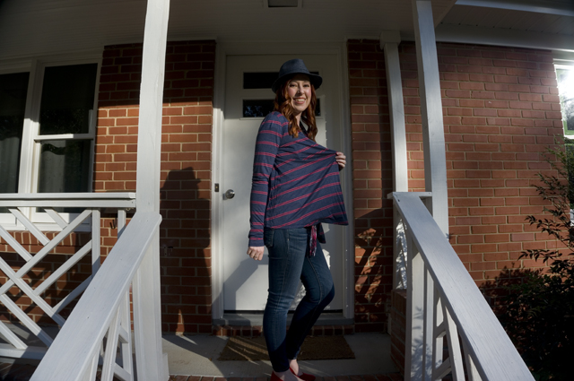 Caitlyn is turned sideways and holding out one side of her open-front cardigan to show its drape