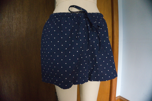 The front of a pair of drawstring pajama shorts hanging on a dress form