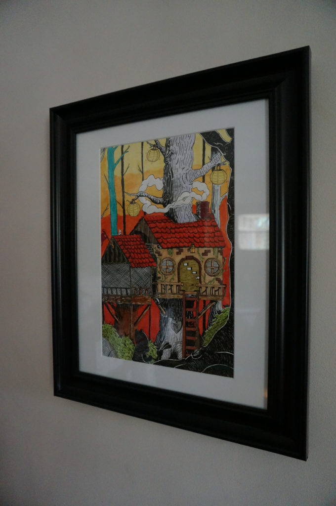 A framed illustration of a cottage-style treehouse with the silhouettes of a cartoon bear and rabbit in the foreground