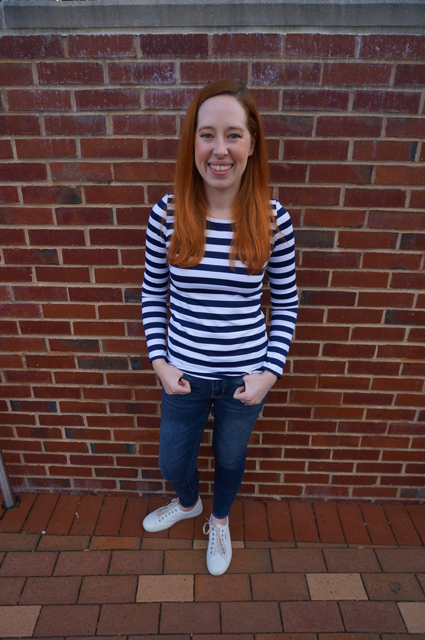 Caitlyn is smiling as she stands with her thumbs hooked through her belt loops and shows off the long-sleeve striped t-shirt she made