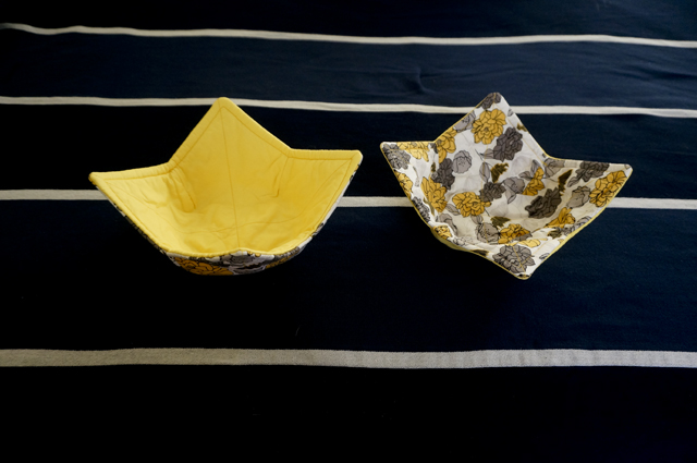 Two bowl cozies with a yellow and grey floral exterior fabric and a solid yellow interior fabric