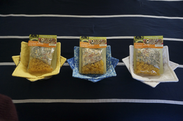 Three pairs of nested bowl cozies, each holding a bag of pre-packaged soup mix