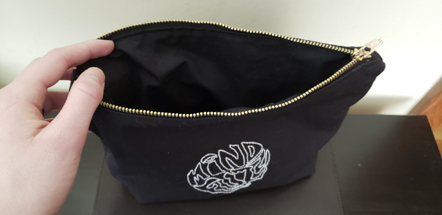 A black zippered pouch with the zipper opened to reveal a cleanly finished interior lined in the same black fabric