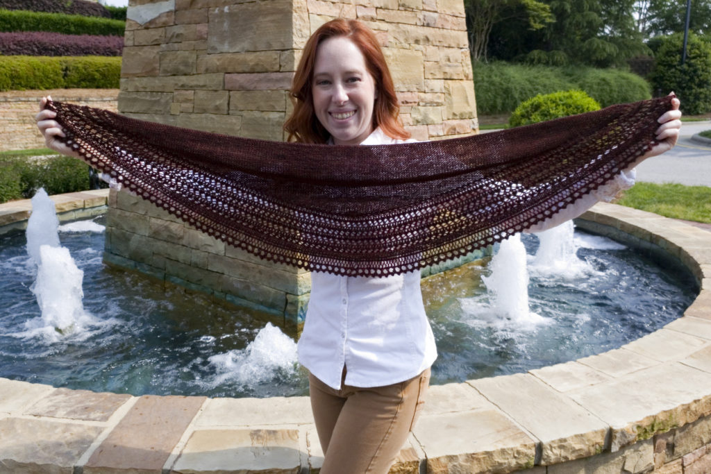 Caitlyn is holding up her Henslowe shawl to show it has a wingspan of about 4 feet and a depth of about 1 foot.