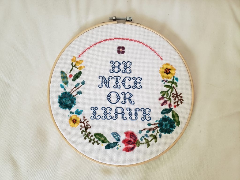 Cross stitch with a floral border framed in a wooden hoop